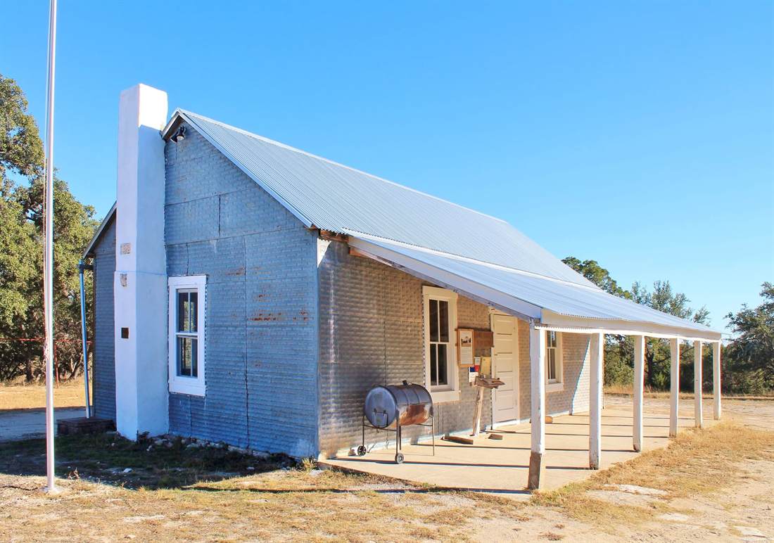 The restored Cave Creek School House under a clear Texas sky.